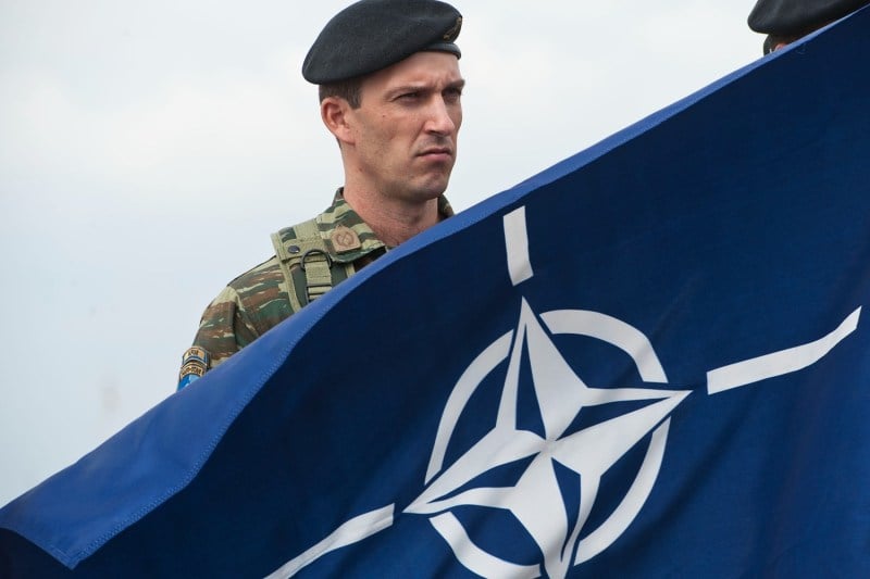 A member of NATO-led peacekeepers holds the NATO flag during the change of command ceremony in Pristina, Kosovo, on Sept. 3, 2014.