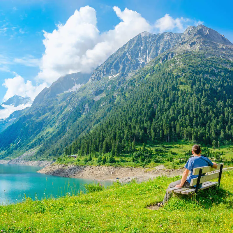 Young Man Sitting By An Alpine Lake In South Tyrol, Italy, Alpine Europe