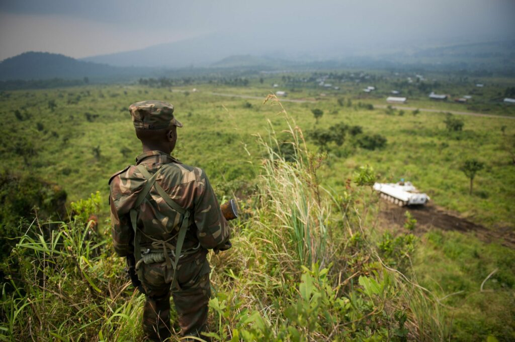 A soldier from the Armed Forces of the Democratic Republic of the Congo (FARDC) stands guard on a hill overlooking a United Nations tank position near the village of Kibumba I, around 20km from the city of Goma in the Democratic Republic of the Congo