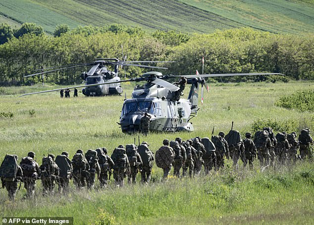 Spanish, German and Dutch soldiers march near helicopters during a NATO exercise in May