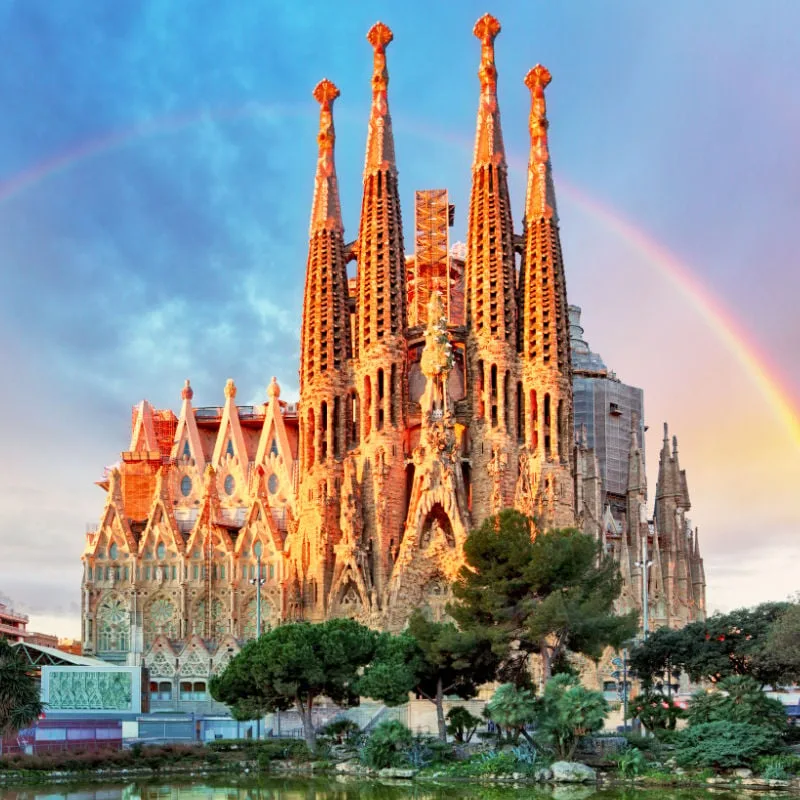 the sagrada familia basilica in barcelona with a rainbow behind