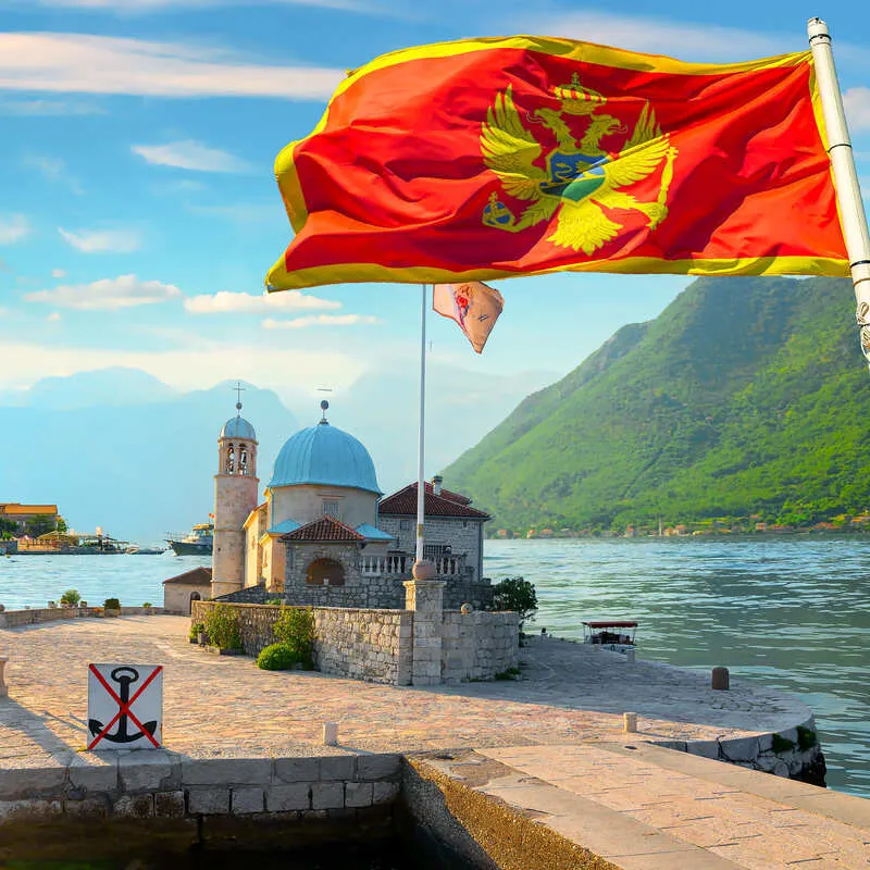Montenegrin Flag Flying In The Wind On A Flagpole On The Small Island Of Our Lady Of Rocks, Bay Of Kotor, Montenegro, Southeastern Europe