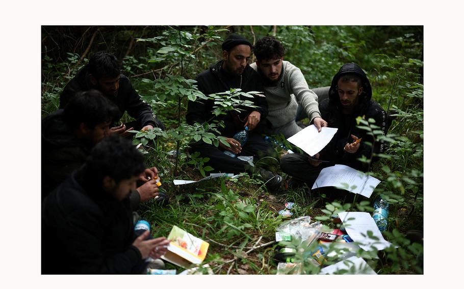 A group of migrants, mainly from Yemen, receive help from humanitarian organisation activists, as they fill up migration documents in the forest near Grudki, Poland, June 4, 2024. 