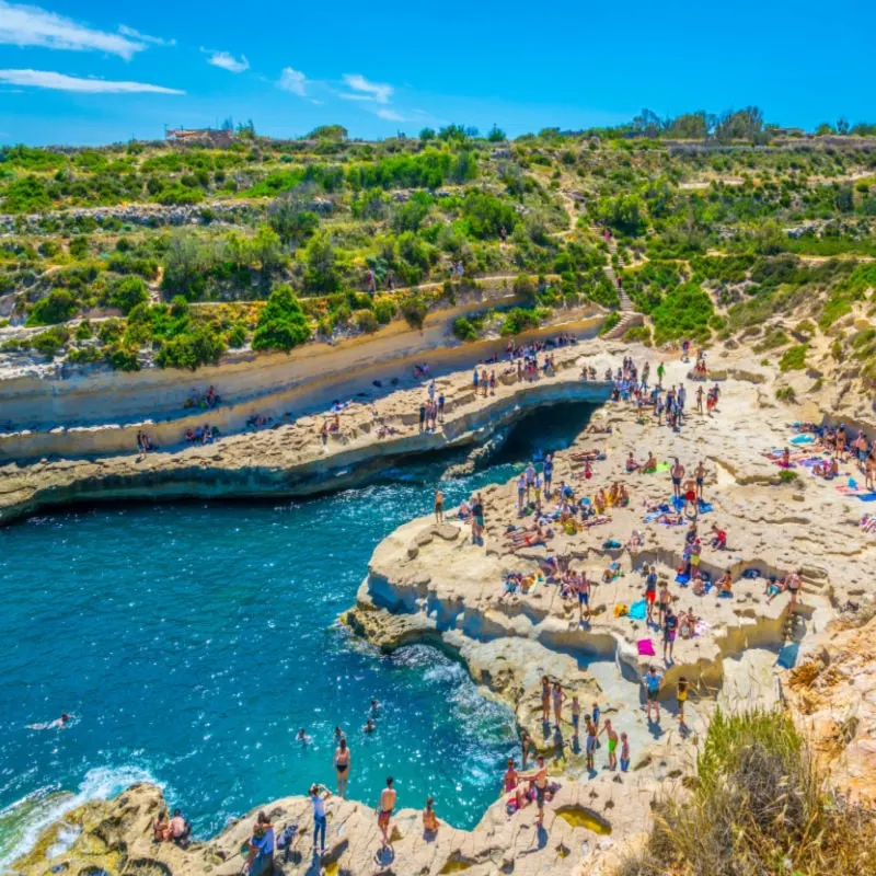 People are enjoying sunny day at Saint Peter's pool near Marsaxlokk, Malta