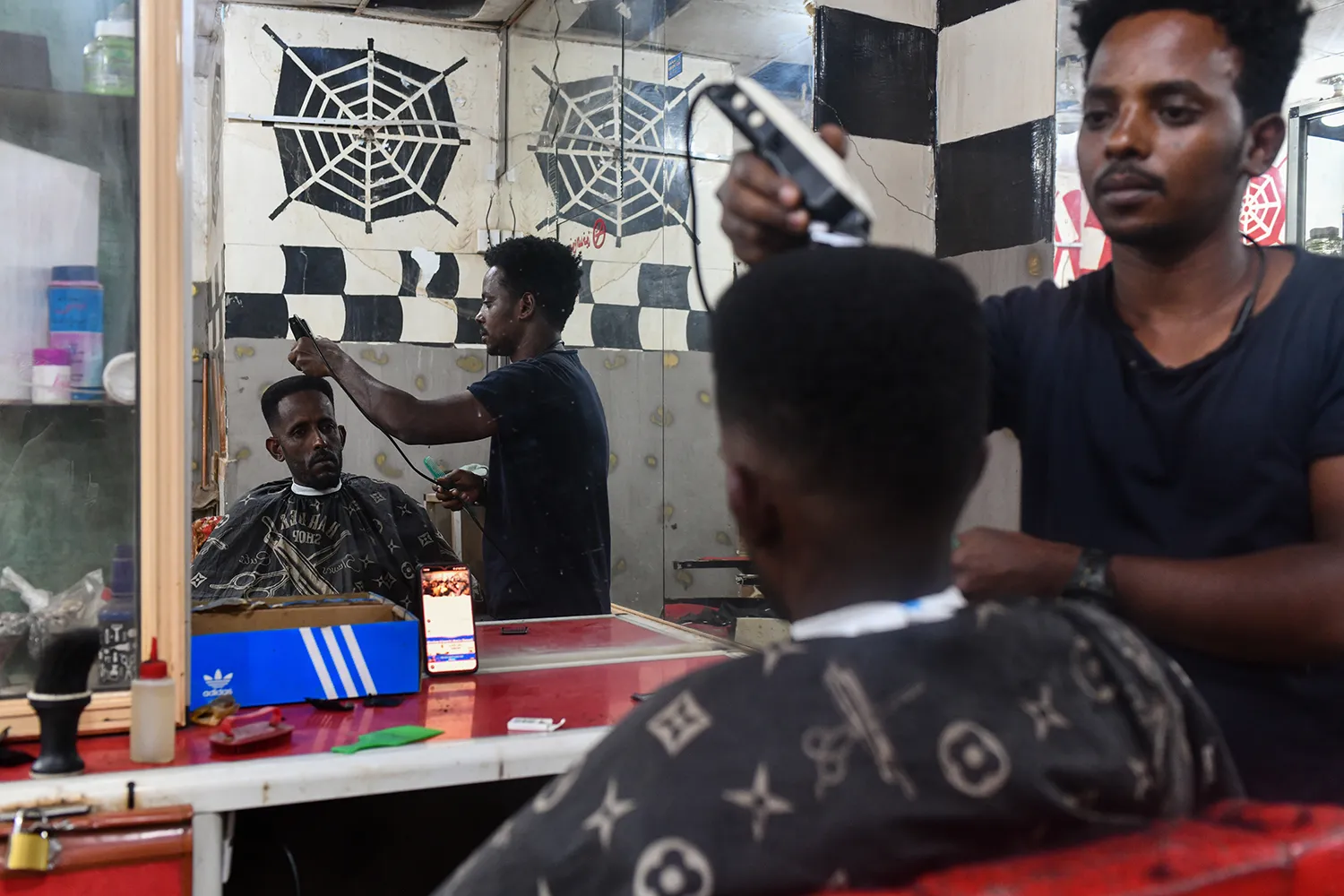 An Eritrean man has his hair cut at a barbershop in Jureif Gharb, a district of Khartoum that for decades hosted the majority of the city’s Eritrean and Ethiopian refugee communities.