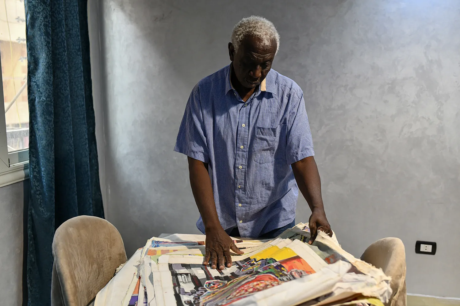 An artist looks down at a stack of his paintings.