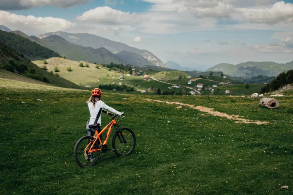 Woman with mountain bike in green valley — Getty Images