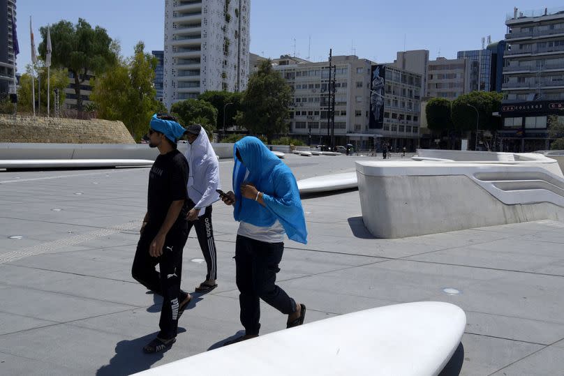 Men take shelter from the sun during a hot day at Elephtherias square in central capital Nicosia, Cyprus.