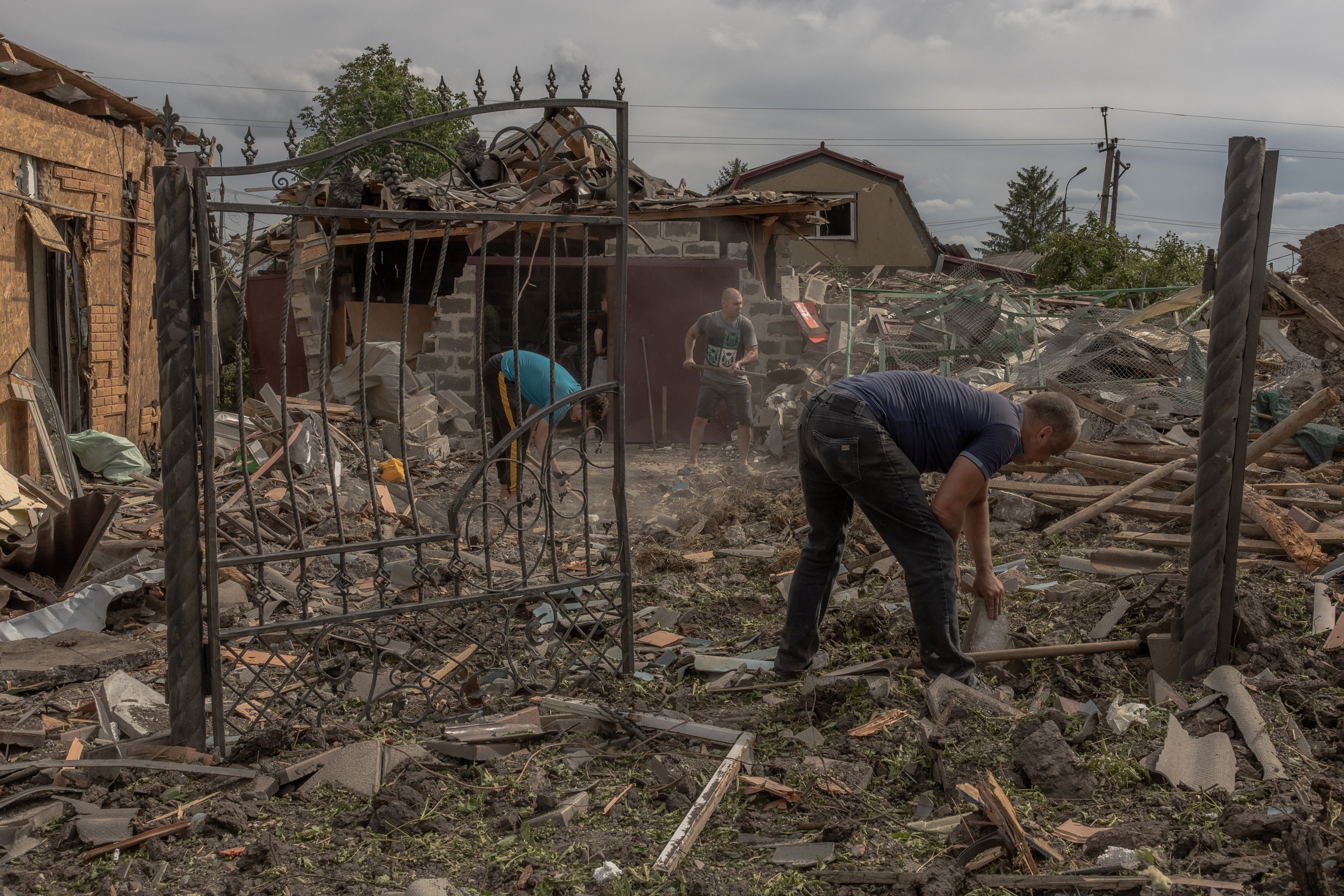 Residents clean debris next to heavily damaged houses following shelling in Pokrovsk,eastern Donetsk region
