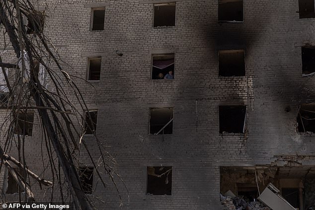People clean debris in an apartment in a heavily damaged residential building following a Russian aerial attack, in Selydove, the eastern Donetsk region on June 27, 2024