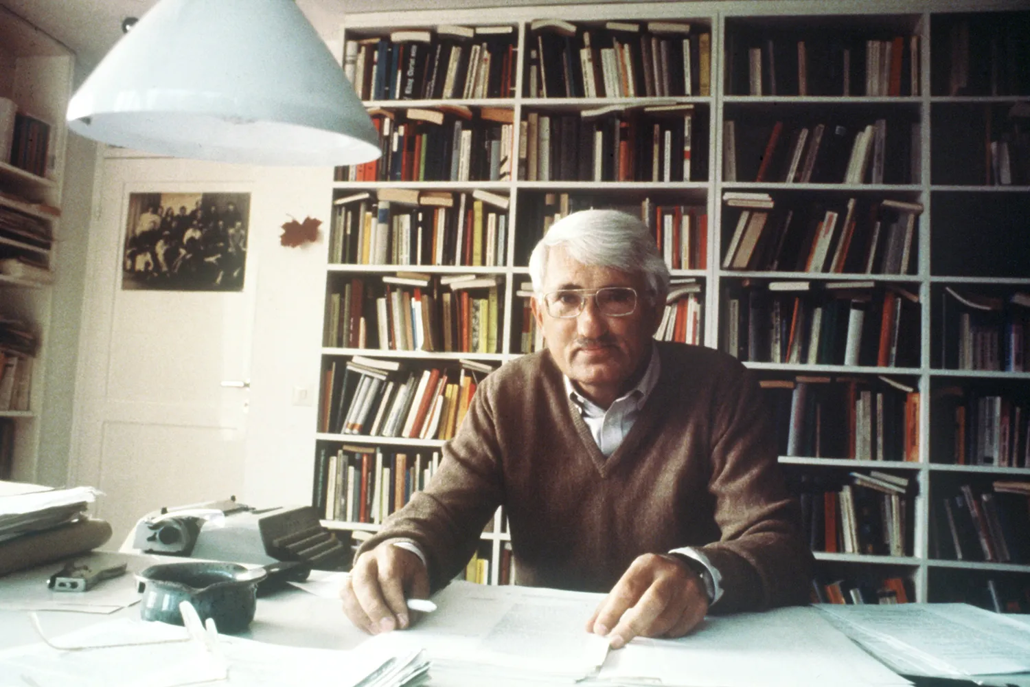 Jürgen Habermas sits at a desk in front of a wall of bookshelves at his home in Starnberg, Germany, in August 1981.