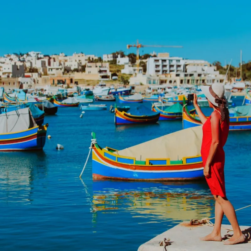 tourist making photo of tranditional maltese boats