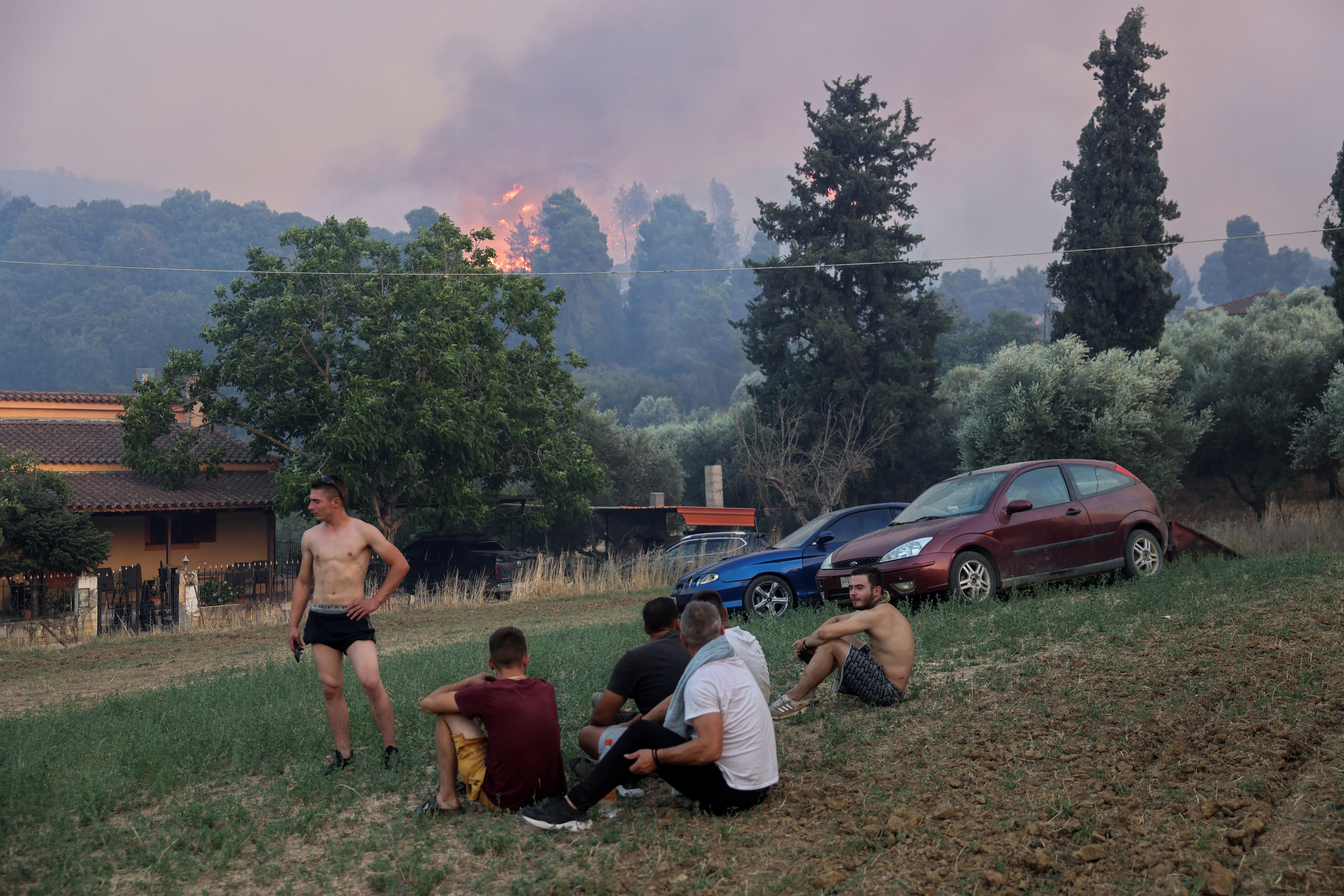 Local residents look on as another wildfire burns in the village of Kalfas in southern Greece on Saturday