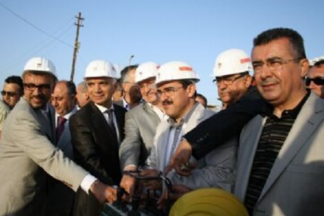 Group of people standing together, some wearing hard hats.